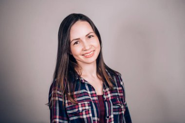 Yatay gri arka plan üzerinde gülümseyen güzel esmer kadın portresi. Olumlu duygular, mutluluk kavramı