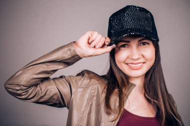 Çekici bir genç esmer kadın kameraya bakarak bir gülümseme ile beysbol şapkalı. Duygusal yüz, mutluluk, öğrenci, sevinç kavramı