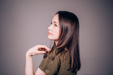 Yana doğru gri arka plan ve gülüyor, gülümsüyor üzerinde duran güzel genç kadın. Kişi, kopya alanı profili.