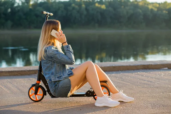 Mujer Rubia Joven Sentada Scooter Hablando Por Teléfono Naturaleza Parque —  Fotos de Stock