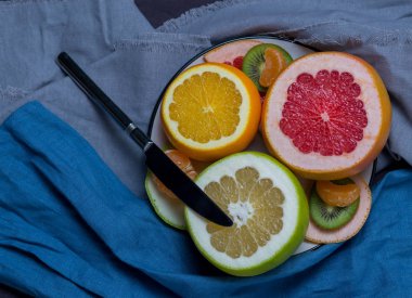 mavi havlu siyah gri arka plan üzerine bir tabak meyve narenciye, dilimlenmiş