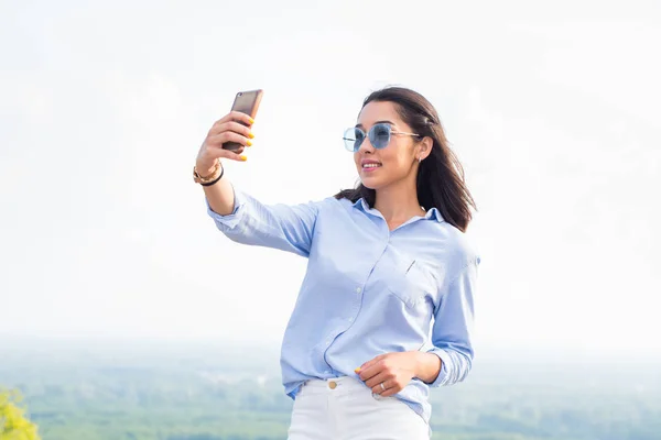 青のメガネで笑顔の美しい女性は 山中の自然の中 Selfies を取る 現代の技術 ライフ スタイル コンセプト — ストック写真