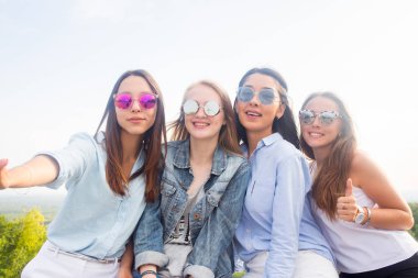 Arkadaşlarım parkta yürürken selfies al. Güneş gözlüğü takıyor dört güzel kadın güzel bir gün olacak. Dört güzel genç öğrenci kız var eğlenceli hafta sonu