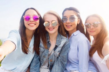 Selfie doğada renkli güneş gözlüklü kız öğrenci grupları yakından. Güzel mutlu çekici kadınlar gülümseme ve kameraya bak