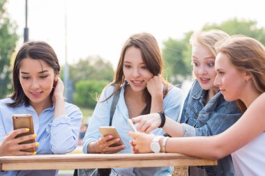Komik kız bir akıllı telefon kullanmak ve bir yaz kafe masada gülmek. Modern teknoloji, dostluk, yaz konsepti