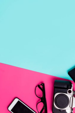 Düz yatıyordu seyahat aksesuarları kopya alanı ile renkli bir arka plan üzerinde. Kamera, smartphone, pembe ve mavi kağıt üzerinde gözlük