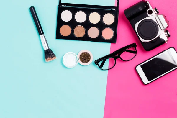 Flat lay of makeup products, smartphone, glasses and film camera on colorful background. Things women photographer