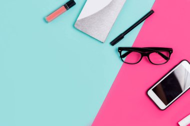 Düz yatıyordu seyyahı ve ofis aksesuarları kopya alanı ile renkli bir arka plan üzerinde. Defter, smartphone, Gözlük, kalem, ruj, dudak parlatıcısı, kıza masada