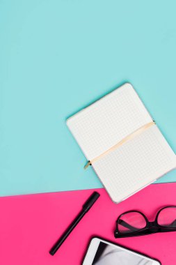 Beyaz Not defteri, Gözlük, smartphone, kalem mavi, pembe renkli arka plan üzerinde kopya alanı ile açın. Öğeleri Office iş kadınları