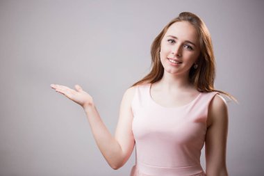 Ürün sunan güzel genç Kızıl saçlı kız tarafına işaret. Etkileyici yüz, ifadeleri duygular. Çekici bir kadın elbise ve kameraya bakarak bir gülümseme ile bir pembe giyer