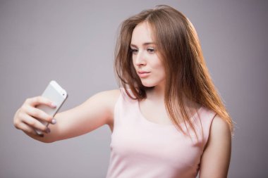 Portre portre genç neşeli readhead kadının selfie smartphone üzerinde gri arka plan üzerinde yapar