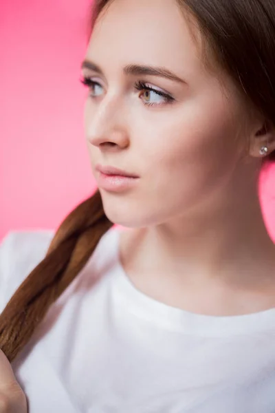 Sideways close up portrait of young girl on a pink background