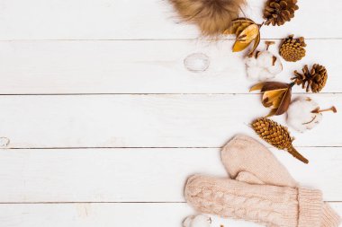 Kış floristik, pamuk, koni ve beyaz ahşap bir masa üstten görünüm, mittens ile örme kürk pon pon özniteliklerini alanı kopyalayın. Kış, yeni yıl, tatil ve dekor kavramı. Düz yatıyordu