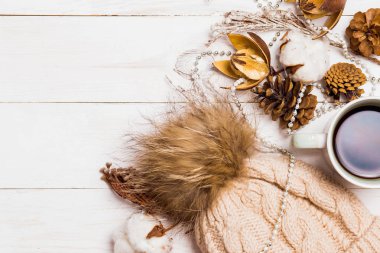 Pon pon, boncuk, dal ve koniler, kopya alanı, üstten görünüm Beyaz ahşap zemin üzerine kahve ile örme bej şapka. Kış, yeni yıl, tatil ve dekor kavramı