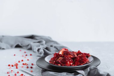 Yatay fotoğraf kırmızı olgun nar kopya alanı ile beyaz bir arka plan gri masada bir kase parçaları. sağlıklı gıda, meyve kavramı