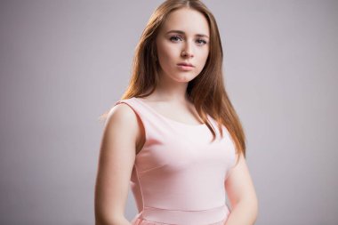 Yatay kameraya gri bir arka plan kopya alanı ile seyir pembe elbiseli güzel genç öğrenci kız portresi