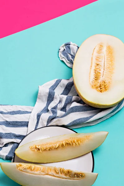 Close up of sliced melon and slices of fruit on a color background, top view.