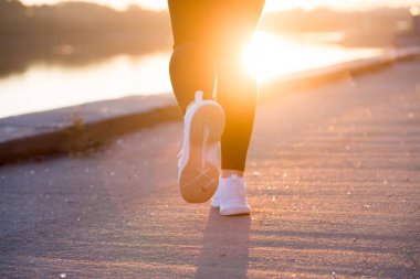 Sporcu kadın atlet ayak günbatımı arka plan üzerinde beyaz spor ayakkabı kadar kapatın