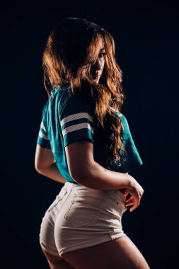 Siyah arka plan üzerine karanlıkta güzel spor fitness ya da dansçı esmer kadın portresi. Gülümseyen ve kameraya bakarak uzun saçlı seksi kız