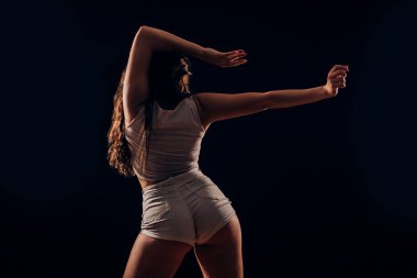 Twerk siyah arka plan üzerine arkadan dans seksi ince yanık tenli kadın. Hareketi, twerk, sağlıklı yaşam, hobi kavramları