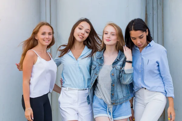 group of female students in summer clothes posing together outdoor and looking at camera. Fashion portrait of young student girlfriends. Lifestyle, youth, people, lifestyle, friendship concept