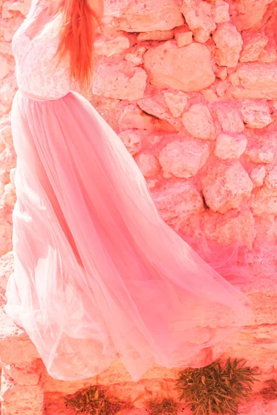 新娘穿着粉红色的婚纱 以大自然中的石头为背景 时尚色彩的概念 2019年 活珊瑚 — 图库照片