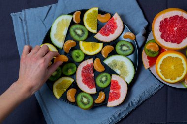 İki tabak kesilmiş meyve parlak sulu Narenciye meyve mutfak havlu üzerinde mavi gri koyu arka plan paçavra, kız için gıda ulaşır