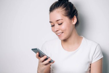 Gülümseyen ve beyaz arka plan üzerinde smartphone kullanarak mutlu genç esmer kadın. Modern teknoloji, Internet, iletişim iletiyi kavramı