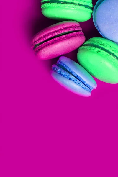 Closeup of colorful sweet macaroons on a purple background with copy space.