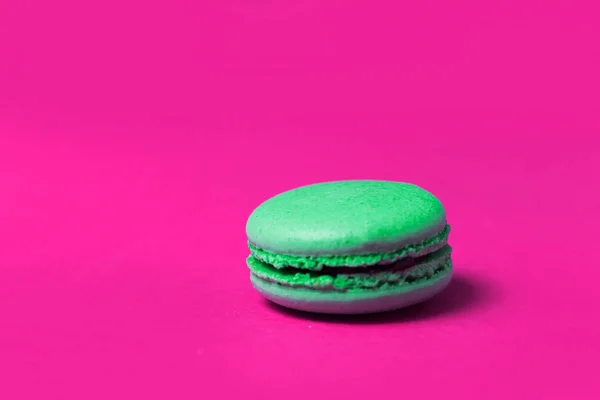 Close up of green sweet macaroon on pink background, selective focus
