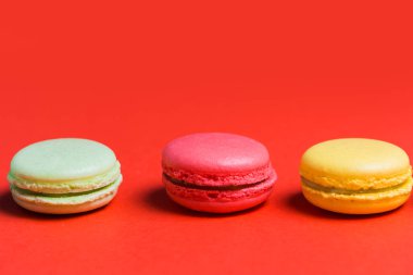 Üç Fransızca macaroons sarı, yeşil ve kırmızı arka plan ile kopya alanı üzerinde pembe yakın çekim