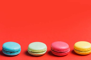 Tatlı ve renkli Fransızca macaroons veya macaron kopya alanı kırmızı zemin üzerine. Tatlı, ev yapımı kek