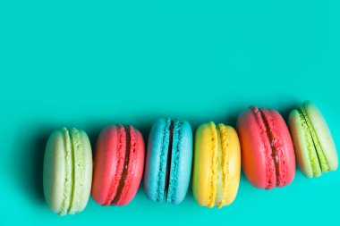 Bir sürü renkli Fransız çerezleri macarons turkuaz arka plan üzerinde kopya alanı ile pasta.