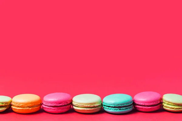 Bright pink background for text with colorful French macaroons, copy space.
