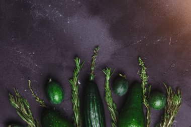 Rosemary, kimyon, salatalık, avokado, feijoa mutfak masasının üstünde siyah arka plan üzerinde. Sağlıklı gıda kavramı
