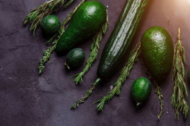 Portre siyah bir zemin üzerine masada yeşil sebze en iyi görünümü. Rosemary, kimyon, salatalık, avokado, feijoa