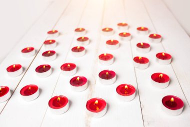 Güzel beyaz ahşap arka plan üzerinde kırmızı mumlar yanan. Sevgililer günü kavramı.