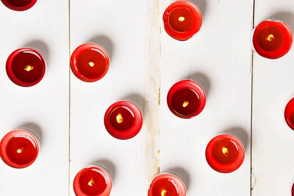 Beyaz ahşap arka plan üzerinde yanan kırmızı küçük mum portre. Düz yatıyordu, en iyi görünümü