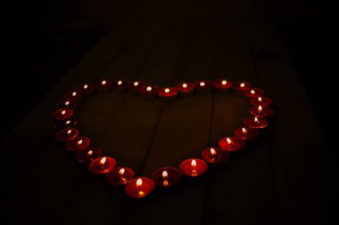 Bir kalp şeklinde karanlıkta küçük mum yakmak. Sevgililer günü kavramı. Düz yatıyordu, en iyi görünümü.