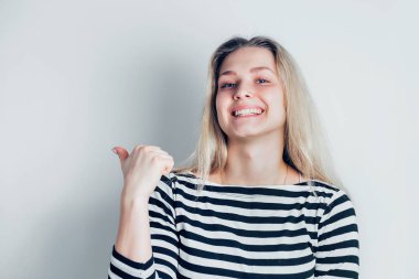 Gülümseyen genç güzel sarışın kadın puan uzakta beyaz arka plan üzerinde izole bir parmak. Olumlu duygular, yüz ifadesi, jest kavramı