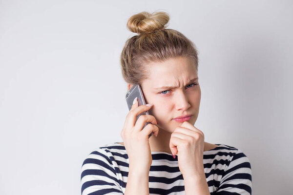 Разочарованная молодая деловая женщина разговаривает по смартфону на белом фоне. Неудачные переговоры, плохие новости, разговоры, плохое настроение
