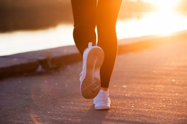 Close up white sneaker of athlete woman runner feet on sunset background