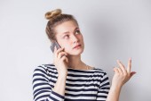 Portrét ženy ležérní držení smartphone a mluvil po telefonu nad bílým pozadím