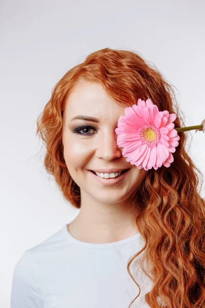 Młoda kobieta gospodarstwa kwiat na jej twarzy — Zdjęcie stockowe