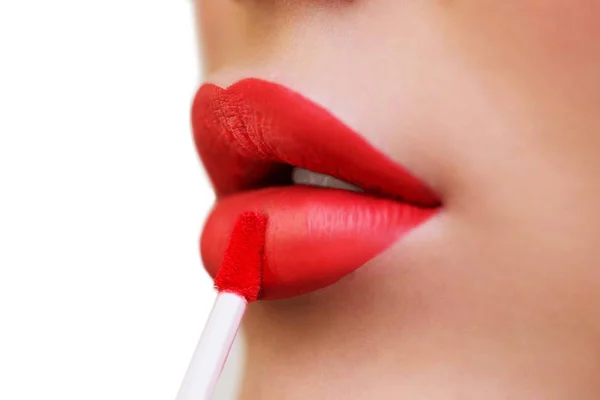 Extrême gros plan sur le modèle appliquant rouge à lèvres rouge. Maquillage de mode professionnel. Appliquer du rouge à lèvres. Bouche ouverte avec dents blanches. Cosmétologie, concept de maquillage mode . — Photo