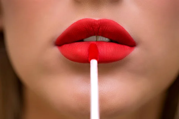 Primer plano retrato de chica atractiva rugiendo sus labios. Ella sostiene lápiz labial rojo. Su boca está suavemente abierta. Brillante brillo labial rojo. Primer plano, piel limpia y bien arreglada — Foto de Stock