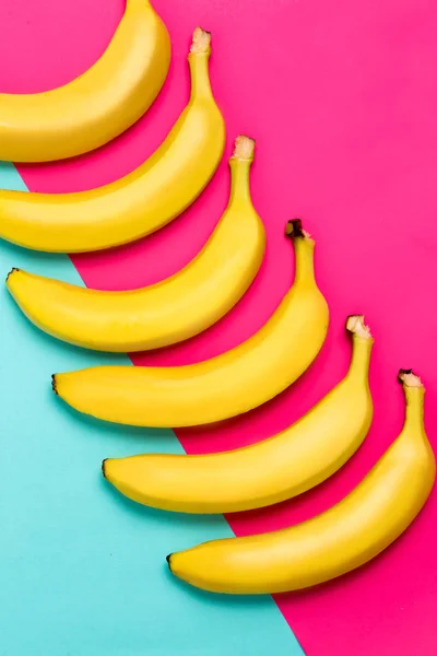 Gros plan de bananes jaunes mûres sur fond rose et bleu . — Photo