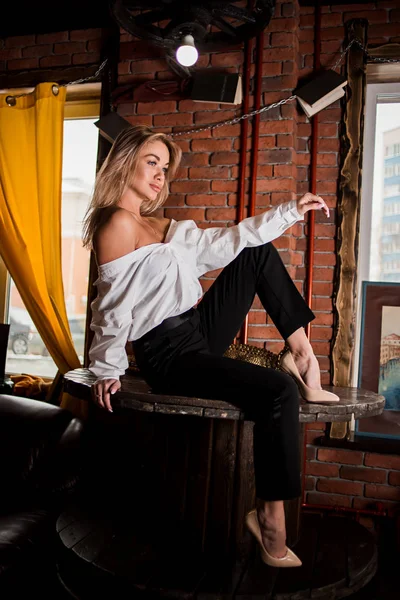 Beautiful woman sitting on table — Stock Photo, Image