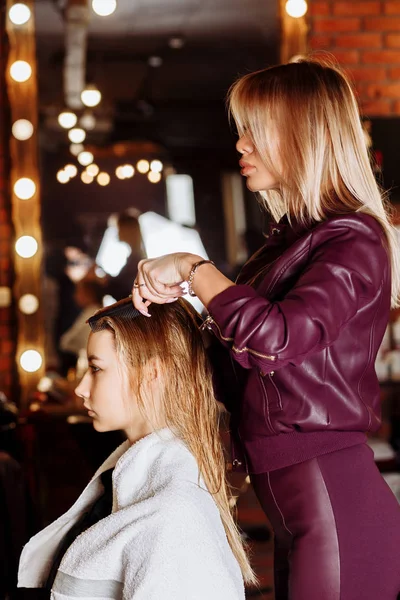 Frisören borsta vått hår av vacker ung blond kvinna i skönhetssalong efter tvättning av hår. Hårets hälsa, skönhetssalong, spa — Stockfoto