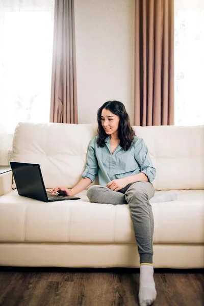 Красива жінка використовує ноутбук вдома на дивані — стокове фото